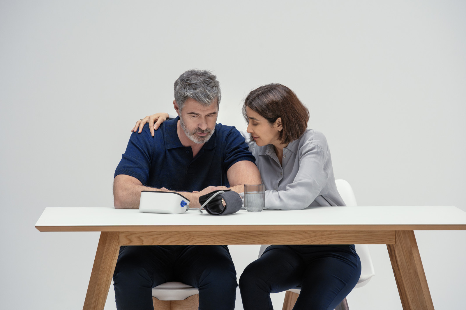 Man and wife at table with blood pressure monitor