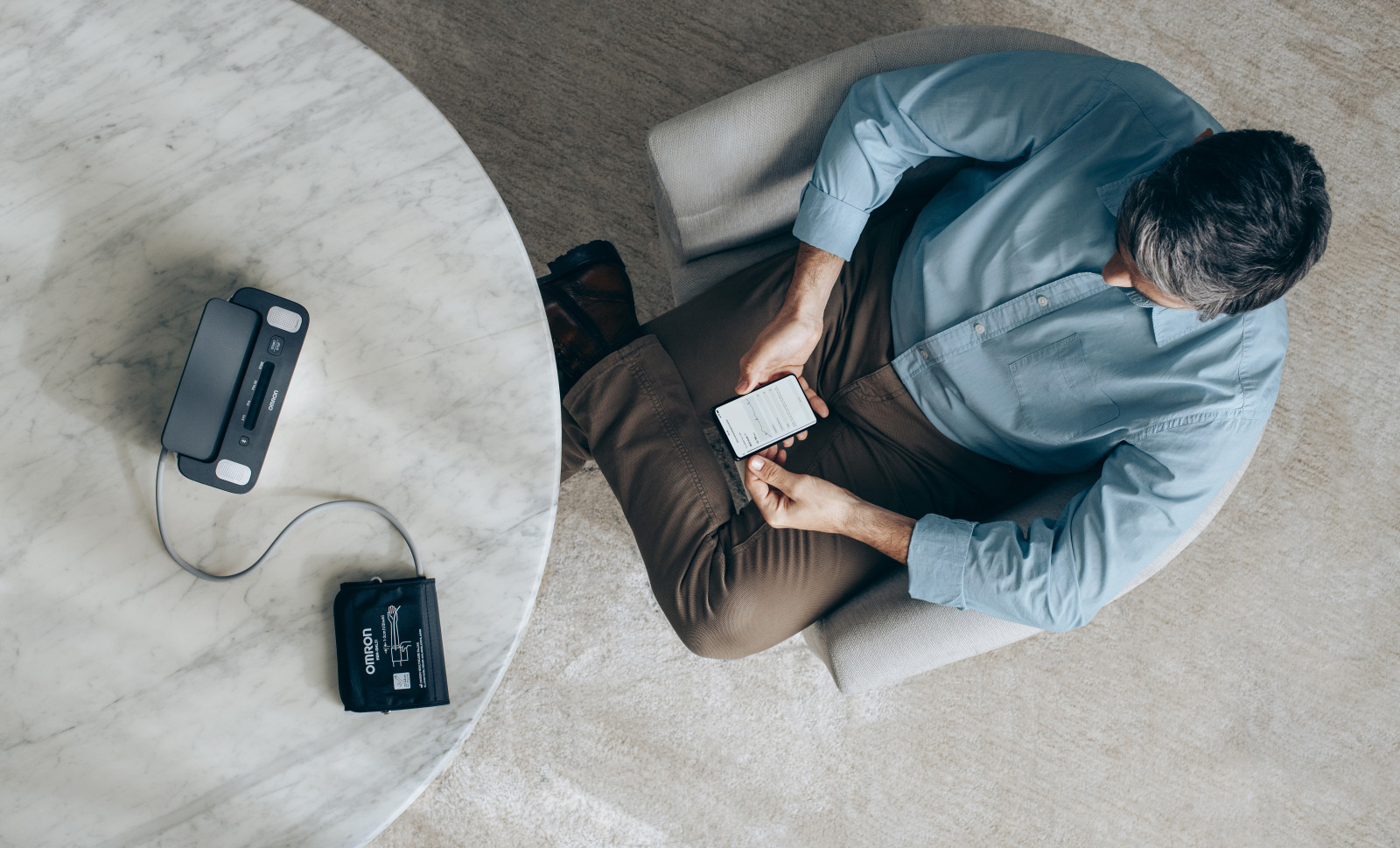 Man looking at phone after taking blood pressure measurement at home
