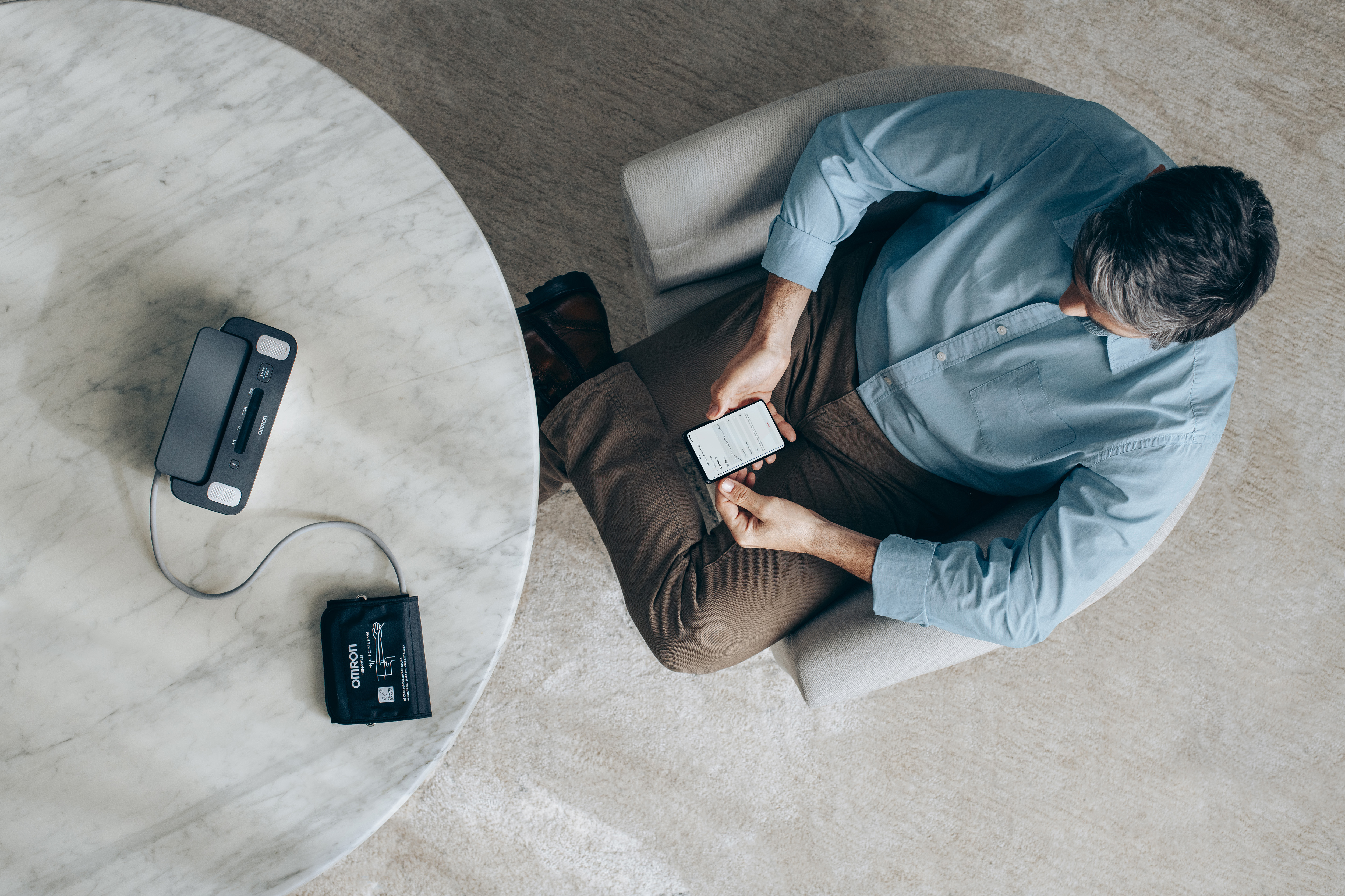 Man looking at phone after taking blood pressure measurement at home