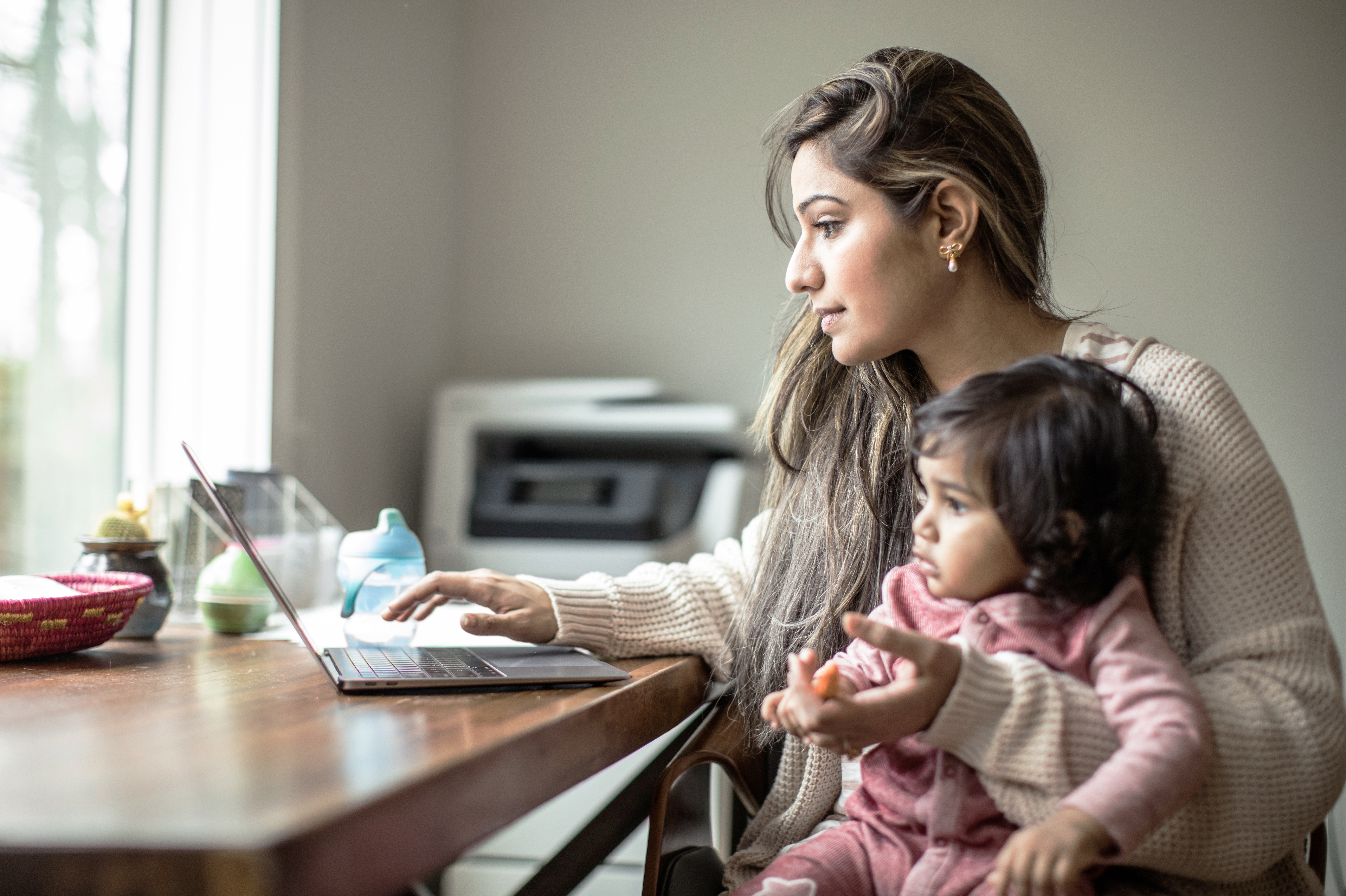 Mother Multi Tasking with Infant Daughter in Home Office